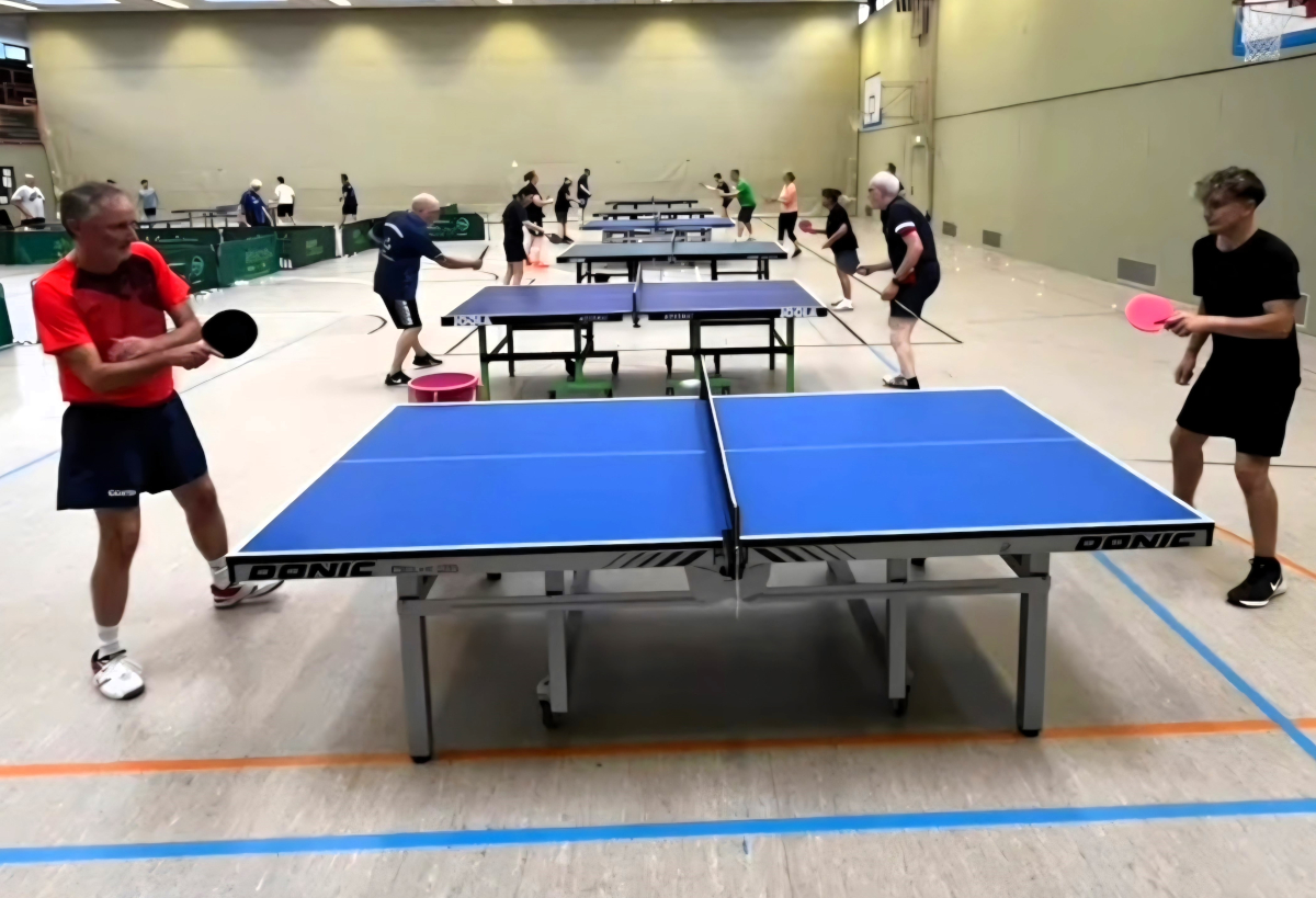 Reihe an Tischtennis-Tischen an denen konzentriert geübt wird