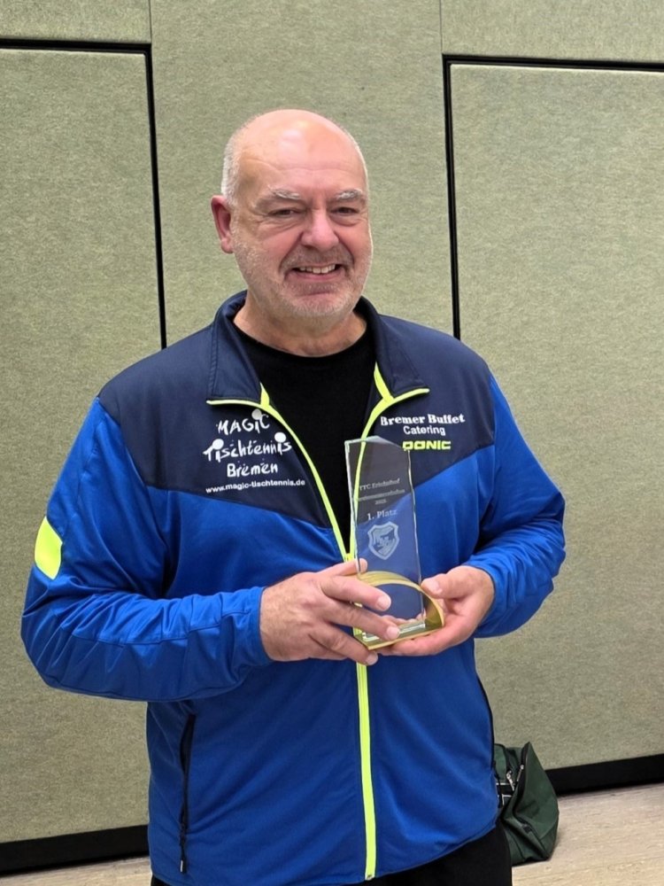 Der lächelnde Sieger mit seiner gläsernen Trophäe für den 1. Platz