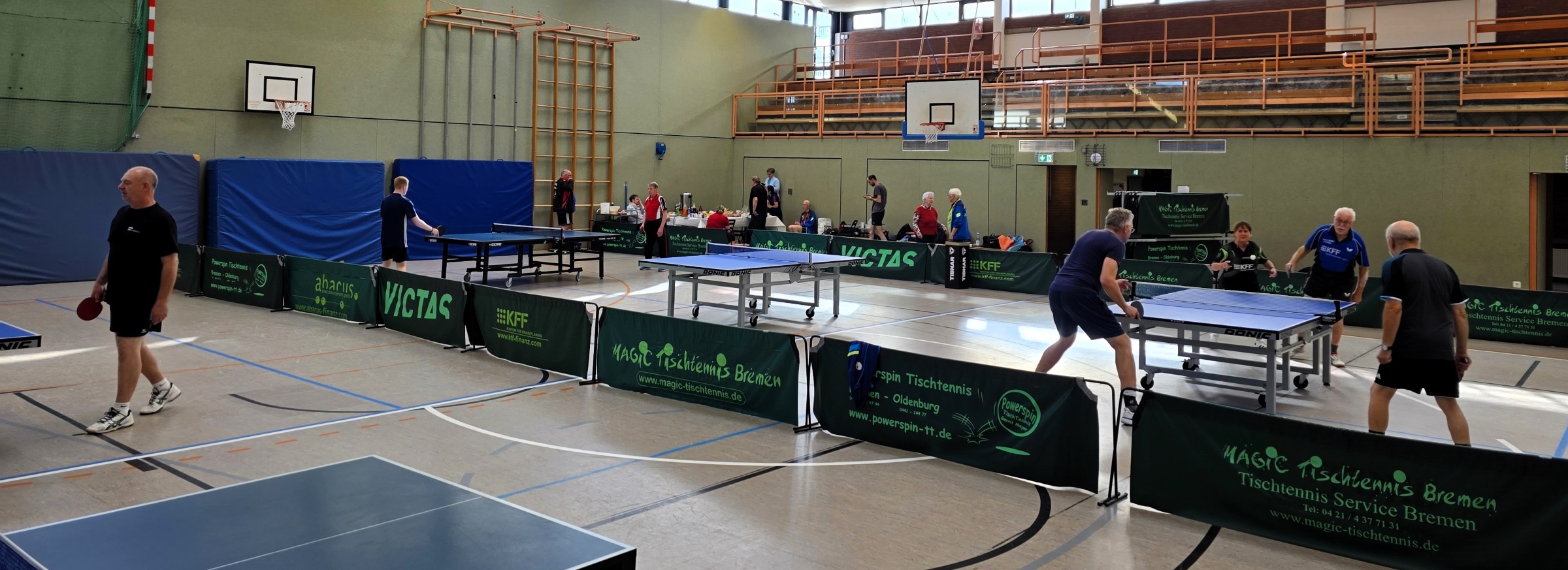 An mehreren Tischen wird von Banden getrennt Tischtennis gespielt