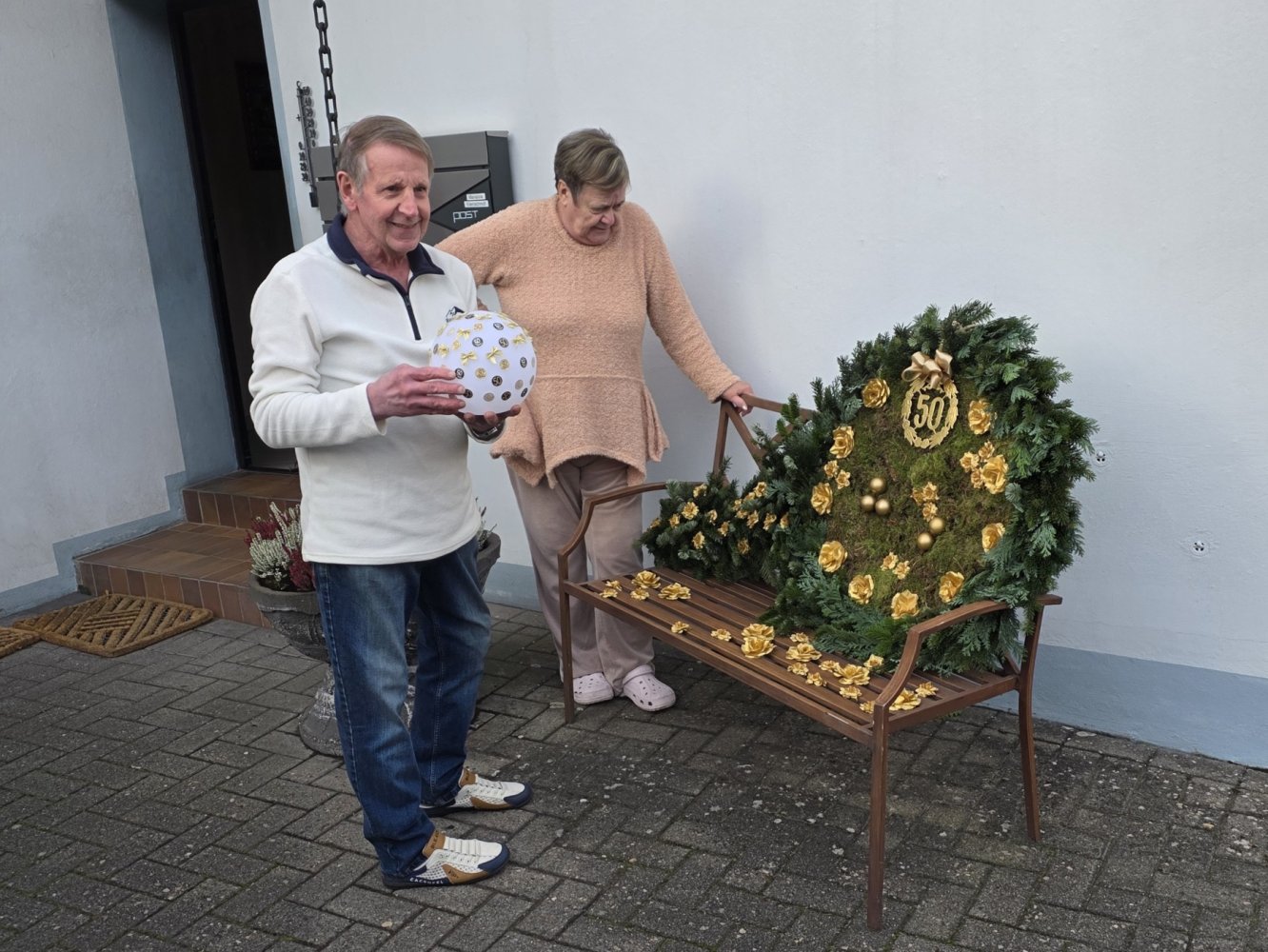 Angela und Klaus begutachten den Kranz in Form eines Tischtennis-Schlägers mit Ball