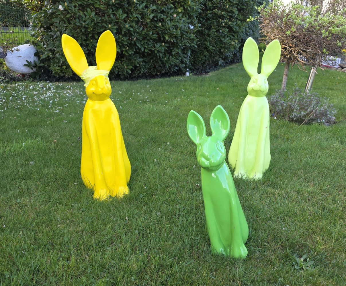 Drei bunte Osterhasen in einem Garten