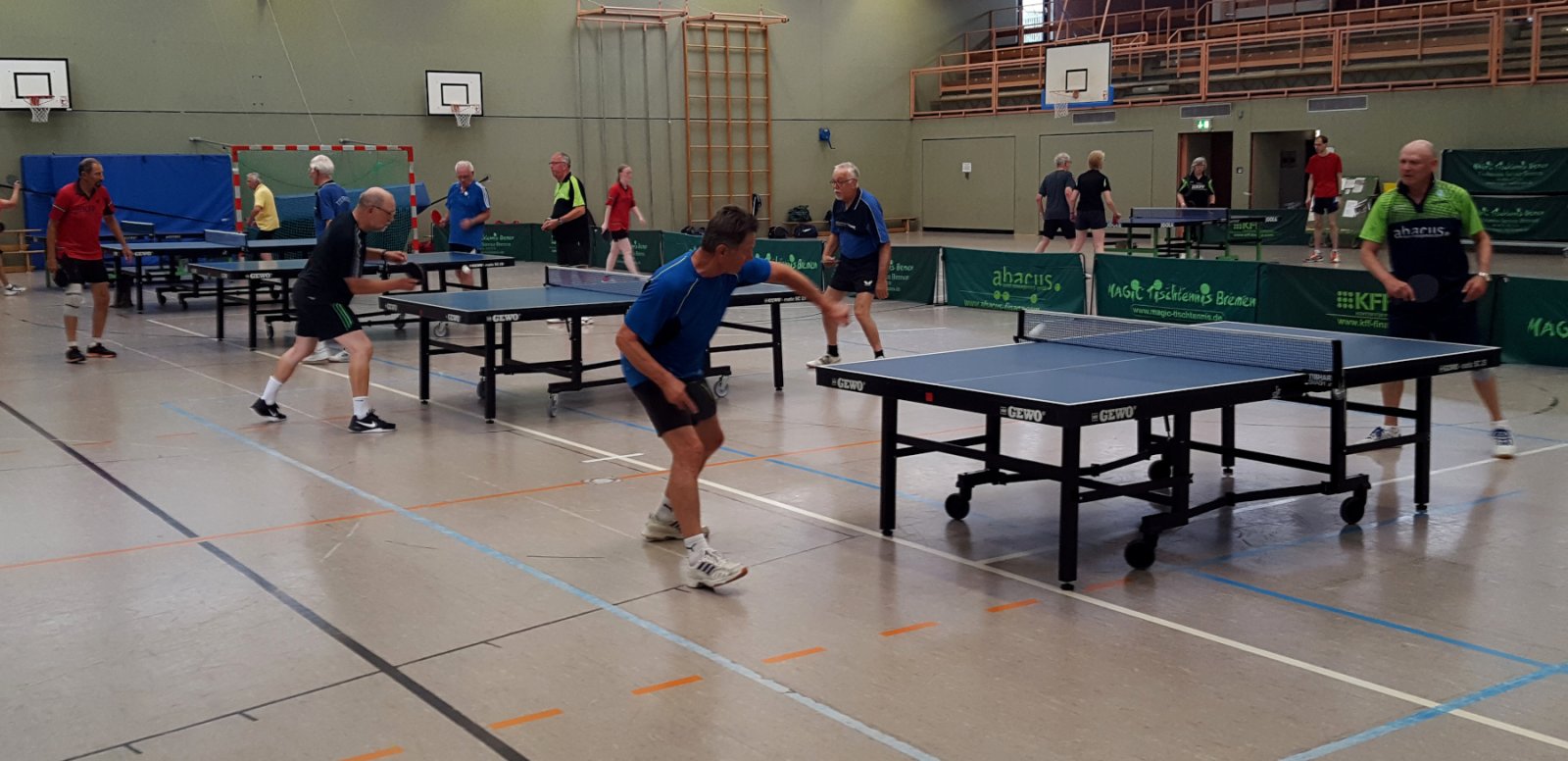 Erwachsenentraining an mehreren Tischtennis-Tischen - es wird Einzel und Doppel gespielt