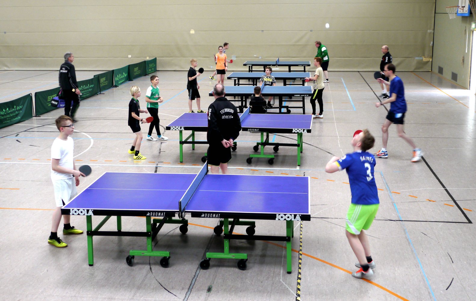 Jugendtraining an mehreren Tischtennis-Tischen unter Anleitung von Trainern